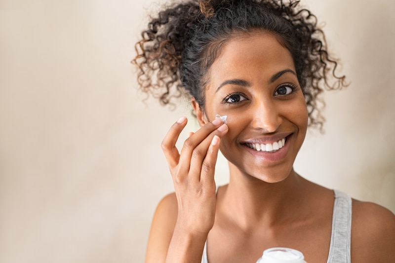 Woman applying facial moisturizer
