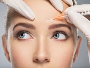 Young woman has Botox injected into her forehead to maintain a youthful look before wrinkles form