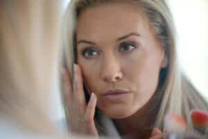 Pretty, middle aged woman looks at her eyes in the mirror to determine