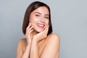30-year-old woman with chic brown hair is happy with her refreshed skin after microneedling.