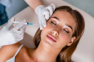 Cute woman has dermal filler injections to restore volume to her cheeks.